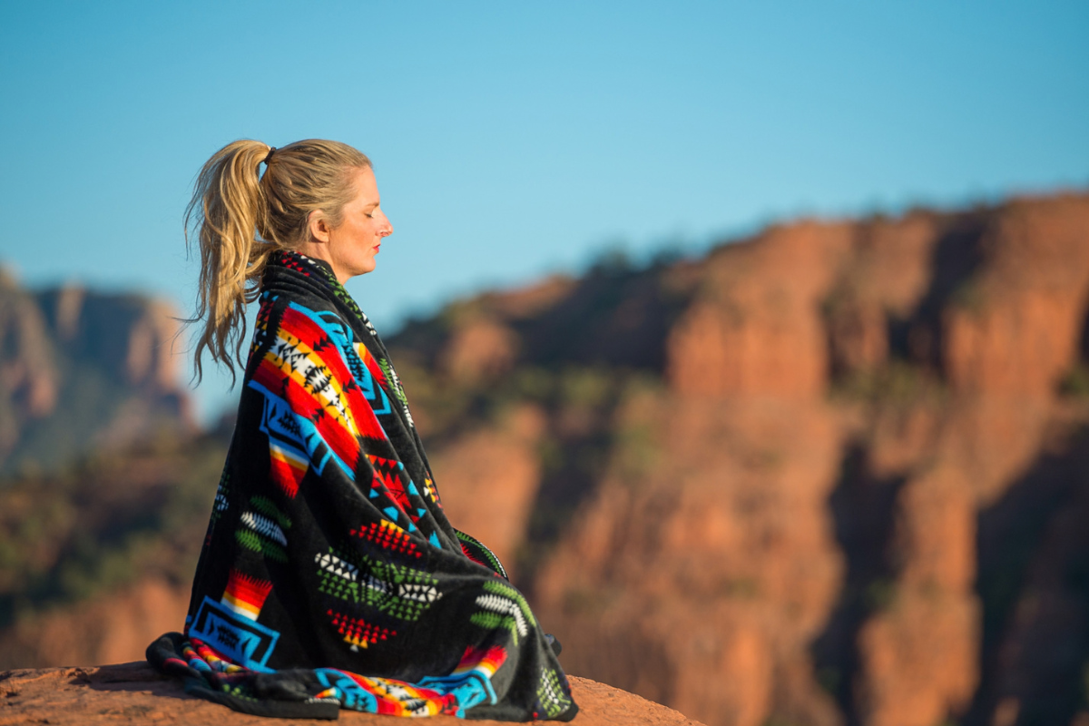 Caroline Culverhouse meditating outdoors in a desert retreat setting